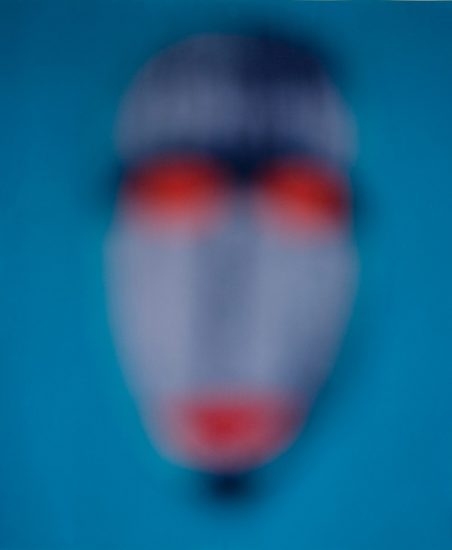 A mask with blue and orange details against a bright blue backdrop.