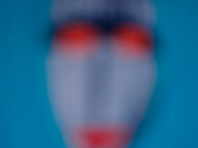 A mask with blue and orange details against a bright blue backdrop.