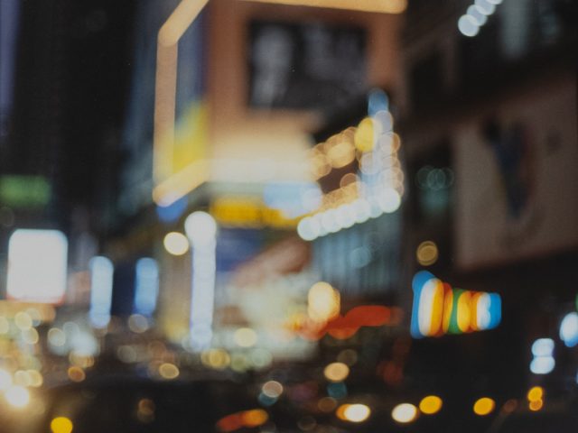 A soft-focus color photograph of a busy urban street with car traffic.