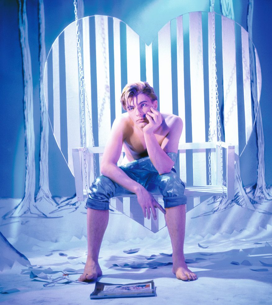 A photograph by James Bidgood of Huck Finn String on a heart shaped swing in a blue room