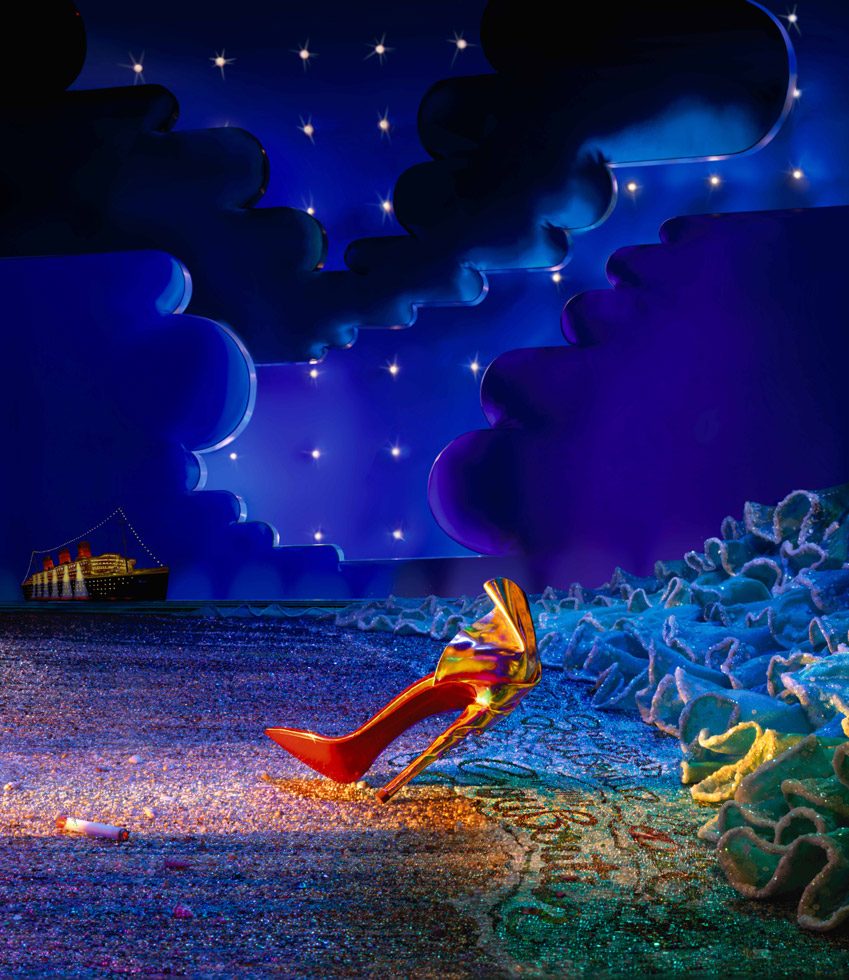 A photograph by James Bidgood of a single heel against a dramatic blue nighttime landscape with a cruise ship