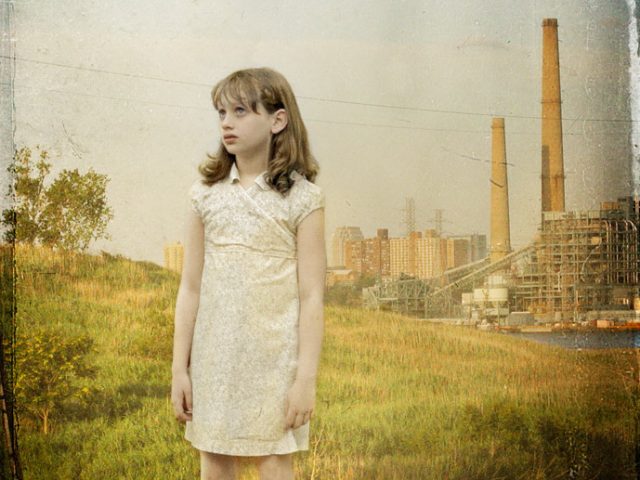 A photograph of a young girl with a look of concern looking slightly up, in the distance is a factory with two smokestacks