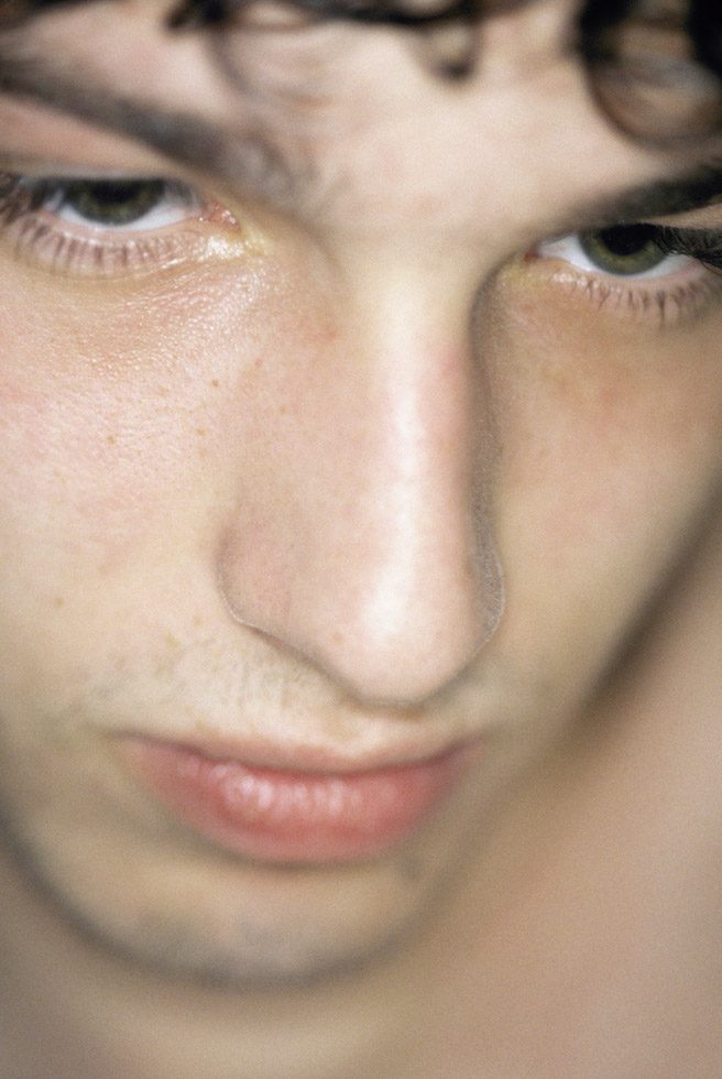 A very close photographic portrait of the face of a young man