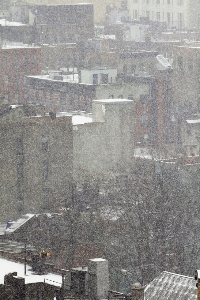 Photograph of snow falling on to roofs in New York City