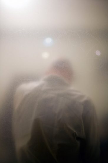 Photograph of the back of a man seen through a slightly hazy window