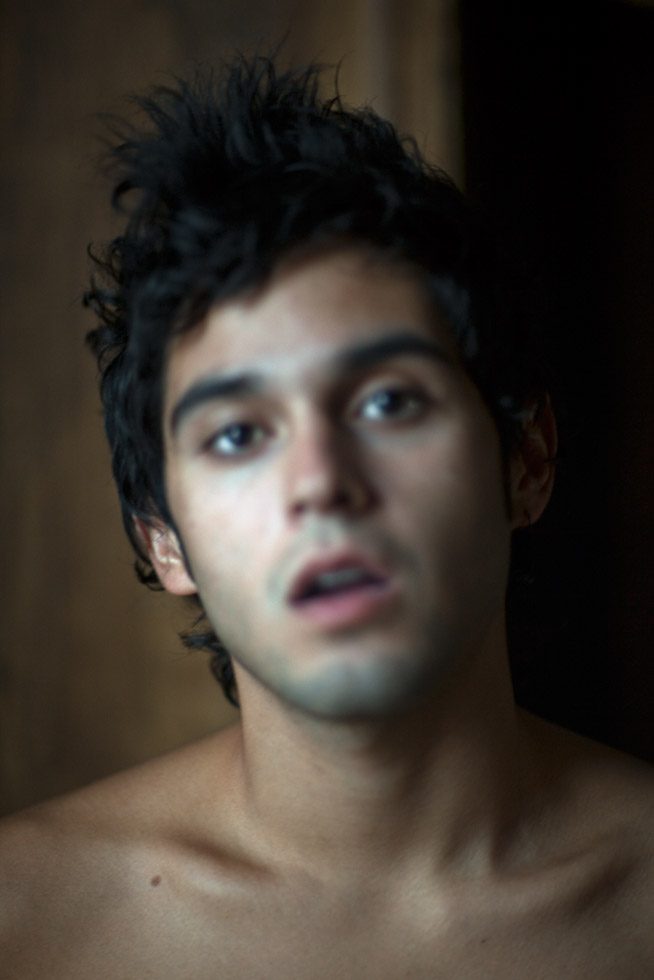 A portrait of the face a man with thick black hair, his mouth is slightly open