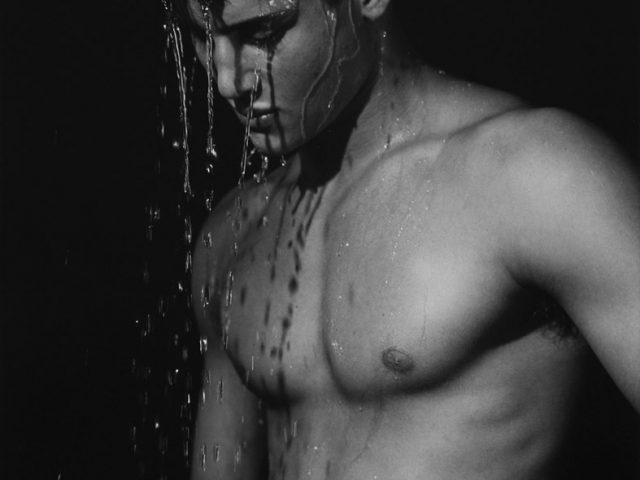 Black and white photograph of a man with water pouring down his head