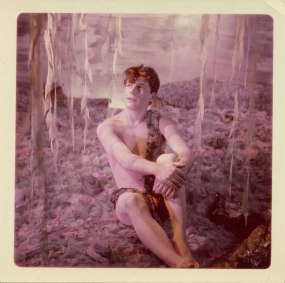 A photograph by James Bidgood of a boy sitting below a willow tree