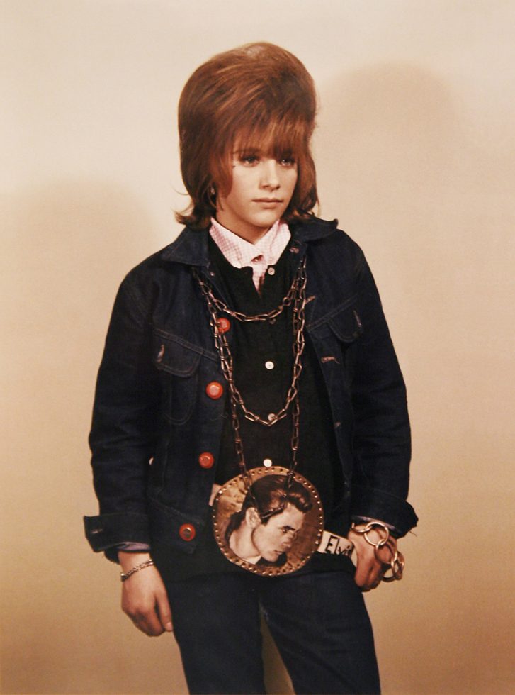 This is a color photograph of a teenage girl with big hair and a James Dean necklace.