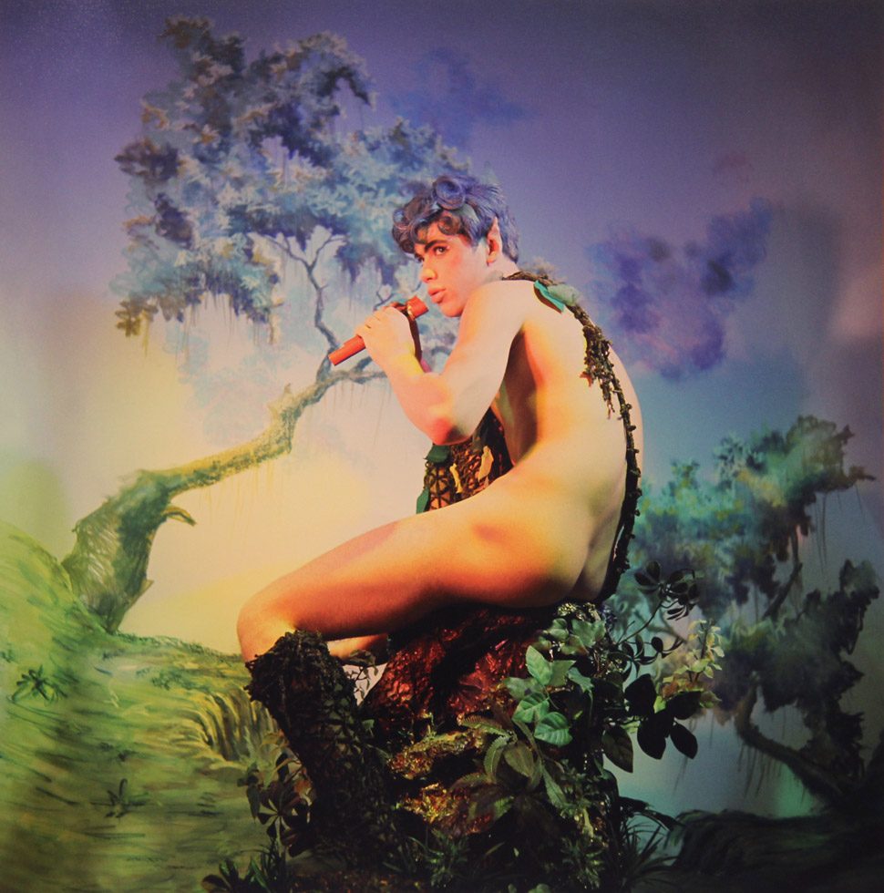 A James Bidgood photograph of pan sitting on a tree branch with flute in mouth, green and purple