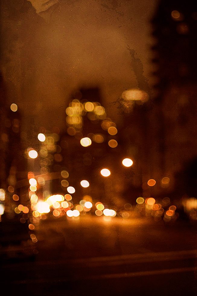 An out of focus photograph of an avenue with cars on it at night