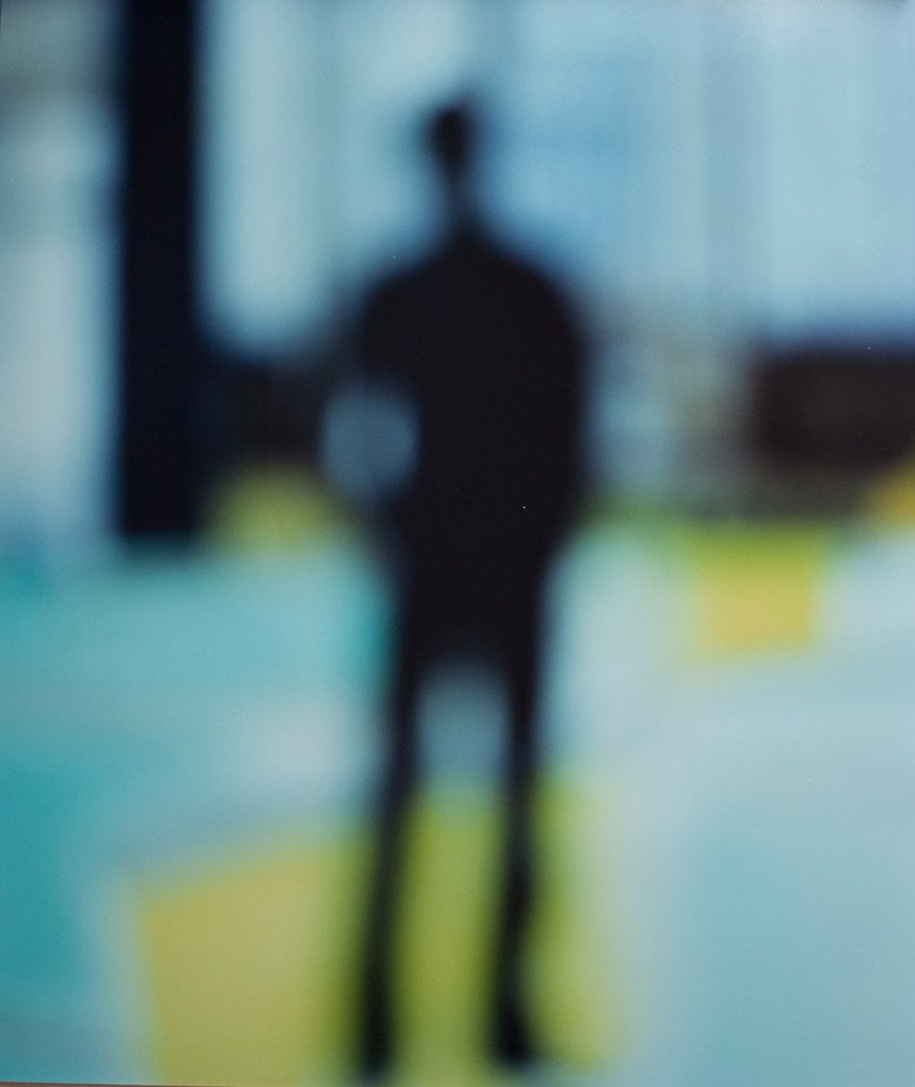 A blurry image of a man's silhouette with yellow and blue in the background.