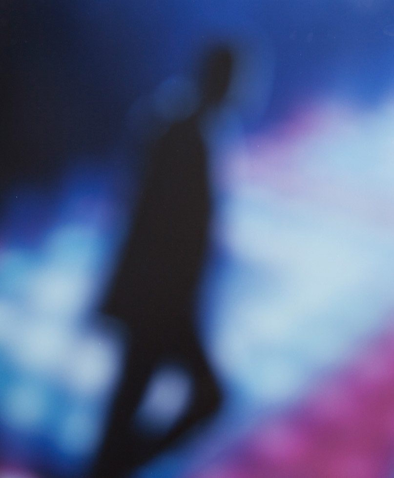 The silhouette of a man walking against a blue and pink background.