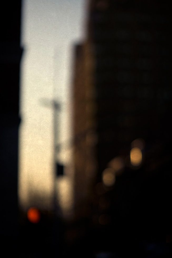 A soft focus photograph of a street in New York right after the sun set with the street quite dark and the sky with the last glow of the sun