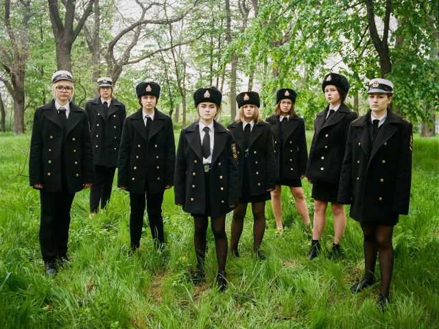 A group portrait in a green forest of eight young women wearing military uniforms.