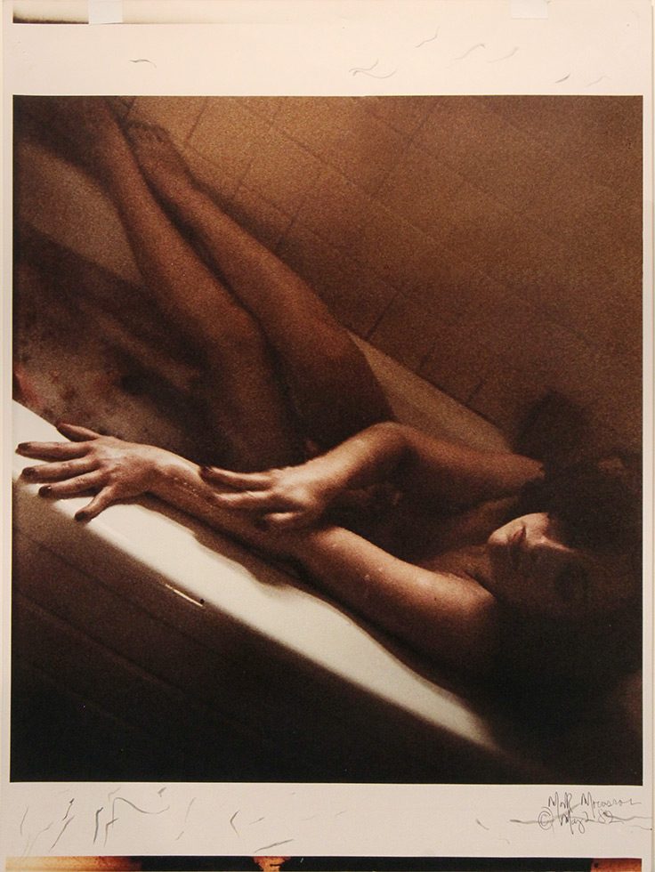 This is a color photograph shot at an angle of a naked woman in a bathtub.