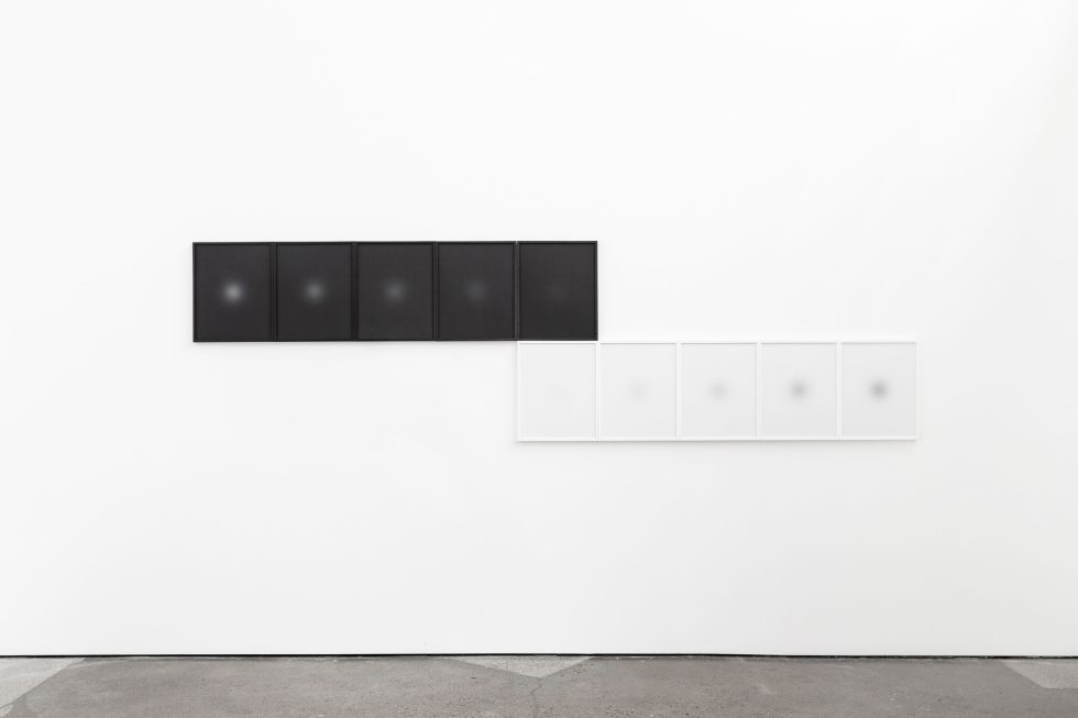This is a photograph depicting two horizontal rows of framed pictures, one white, one black.