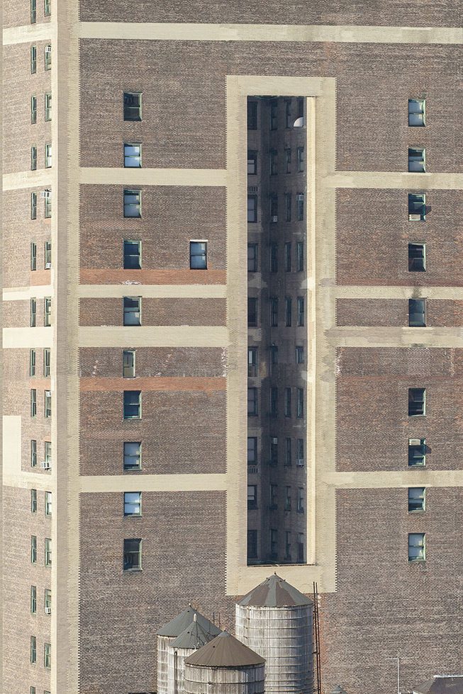 A photograph of a tall building in New York City with a cut out in the front