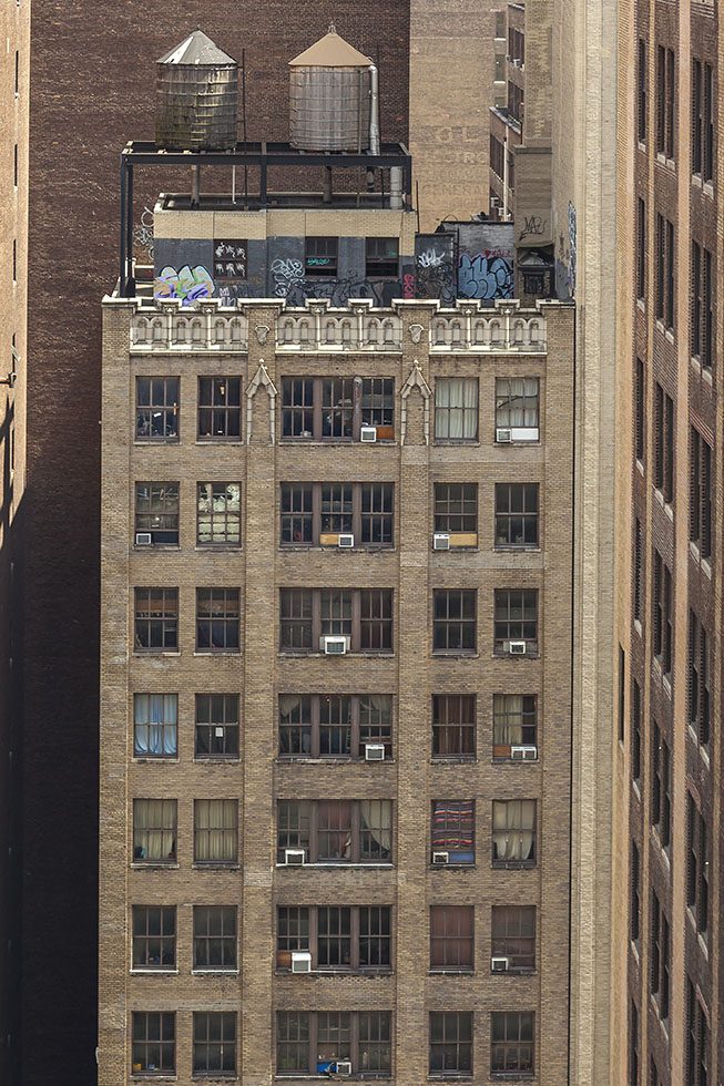 A photograph looking down towards the windows of an apartment building with two water towers on the top