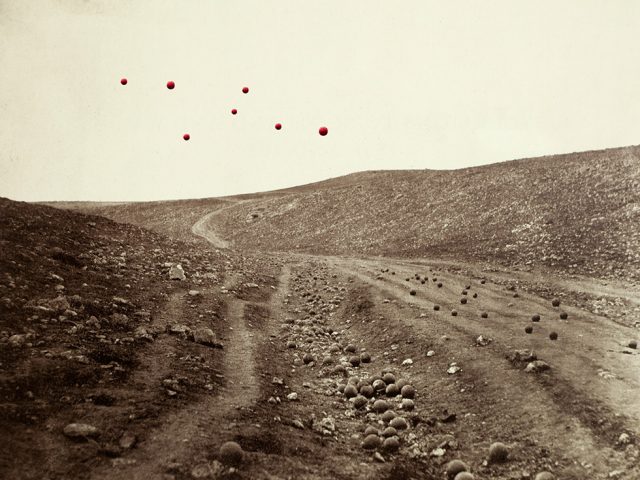 A sepia tone landscape photograph with floating red balls in the sky.