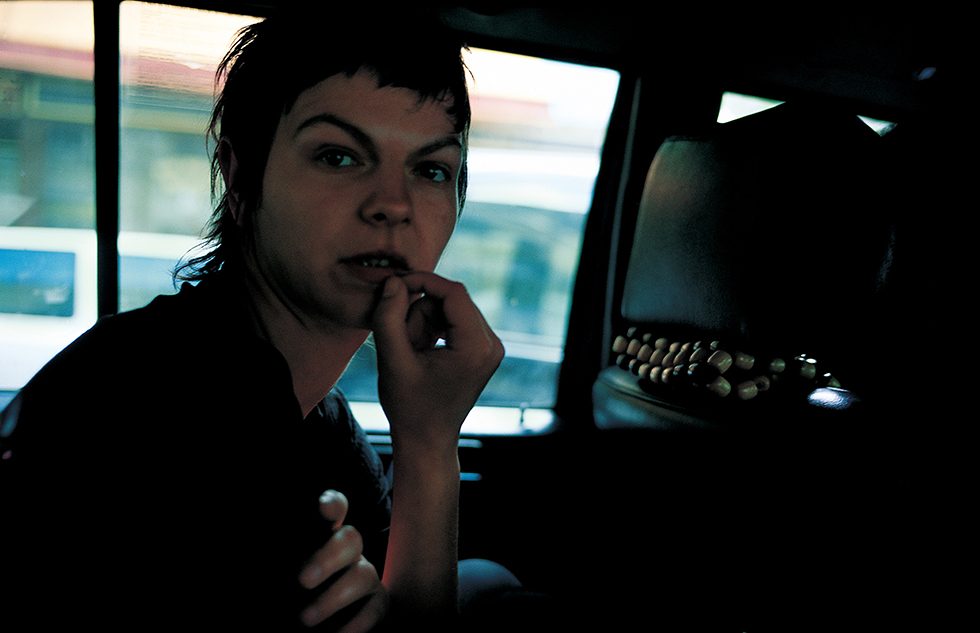 A woman with a shag haircut sitting in a car facing into the camera