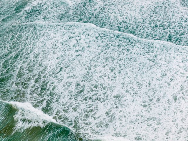 This is a color aerial image of a greenish body of water with frothy white waves.