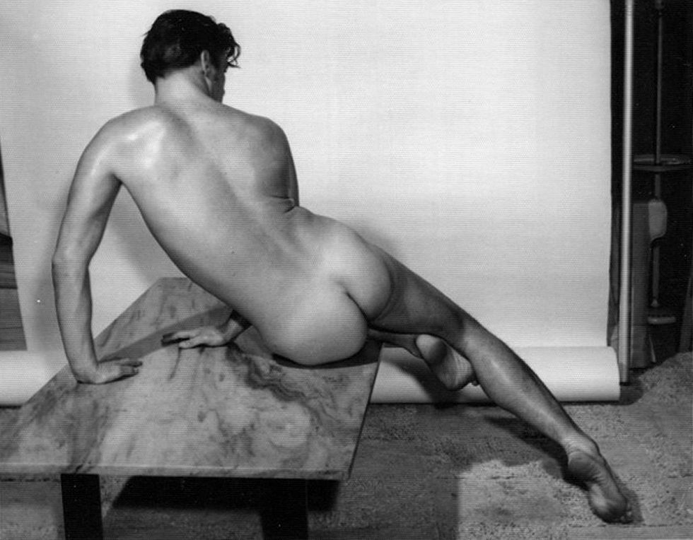 This is a black-and-white portrait of a naked man from behind in an artistic pose.