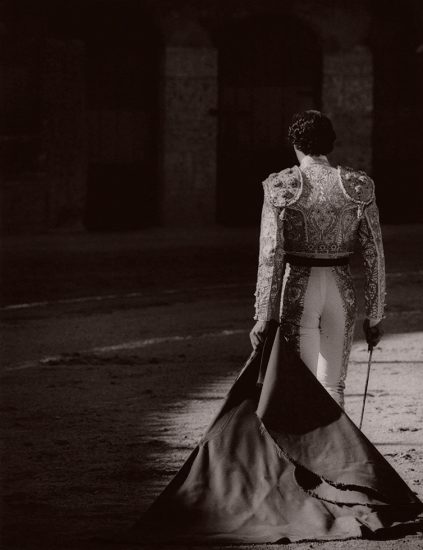 This is a toned black-and-white photograph of a matador from behind wearing a beaded jacket.