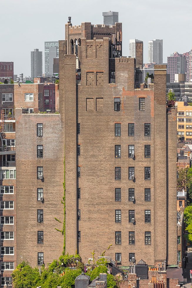 A photograph of the back of a tall, brown brick apartment building in New York City