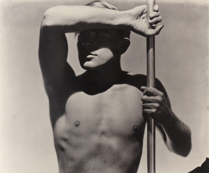 This is a black-and-white photograph by George Hoyningen-Huene of his lover Horst shirtless with his torso on display with a shadow cast across his face.