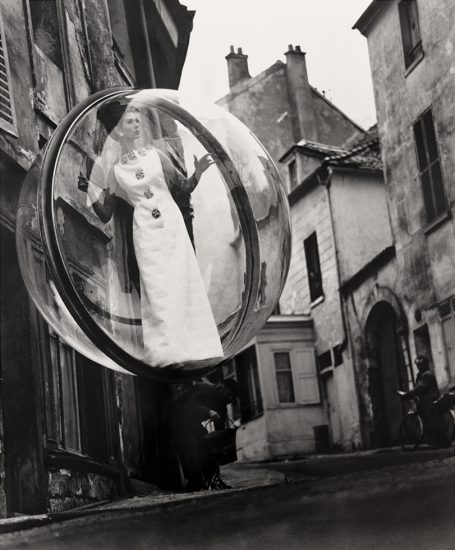 Click for sizes / editions / prices. A photograph of a 1960s fashion model floating in a clear bubble about a city street.