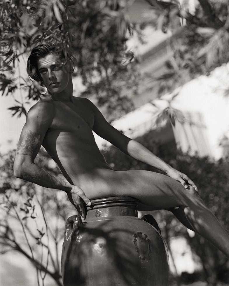 Photograph of a young man sitting on a large clay pot