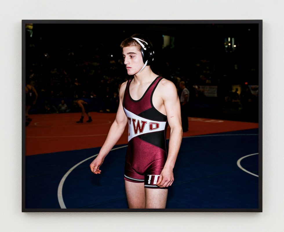 This is a portrait of a young wrestler in his head gear and burgundy singlet.