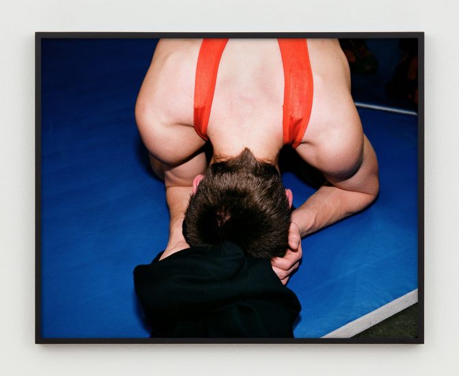 This is a photograph of a wrestler bent over with his head on the mat.