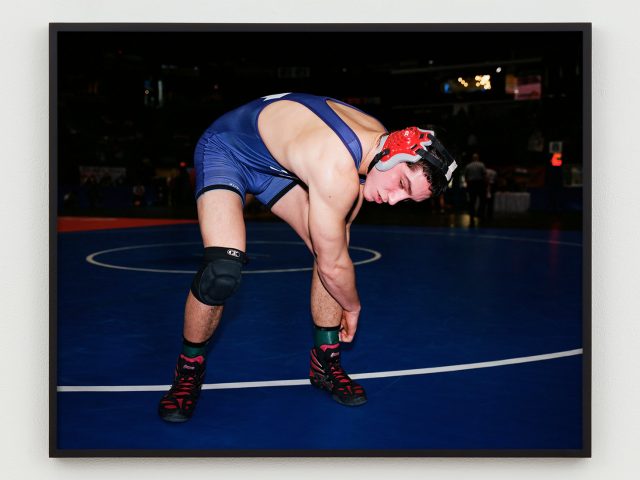 This is a photograph of a wrestler bending over adjusting his ankle straps.