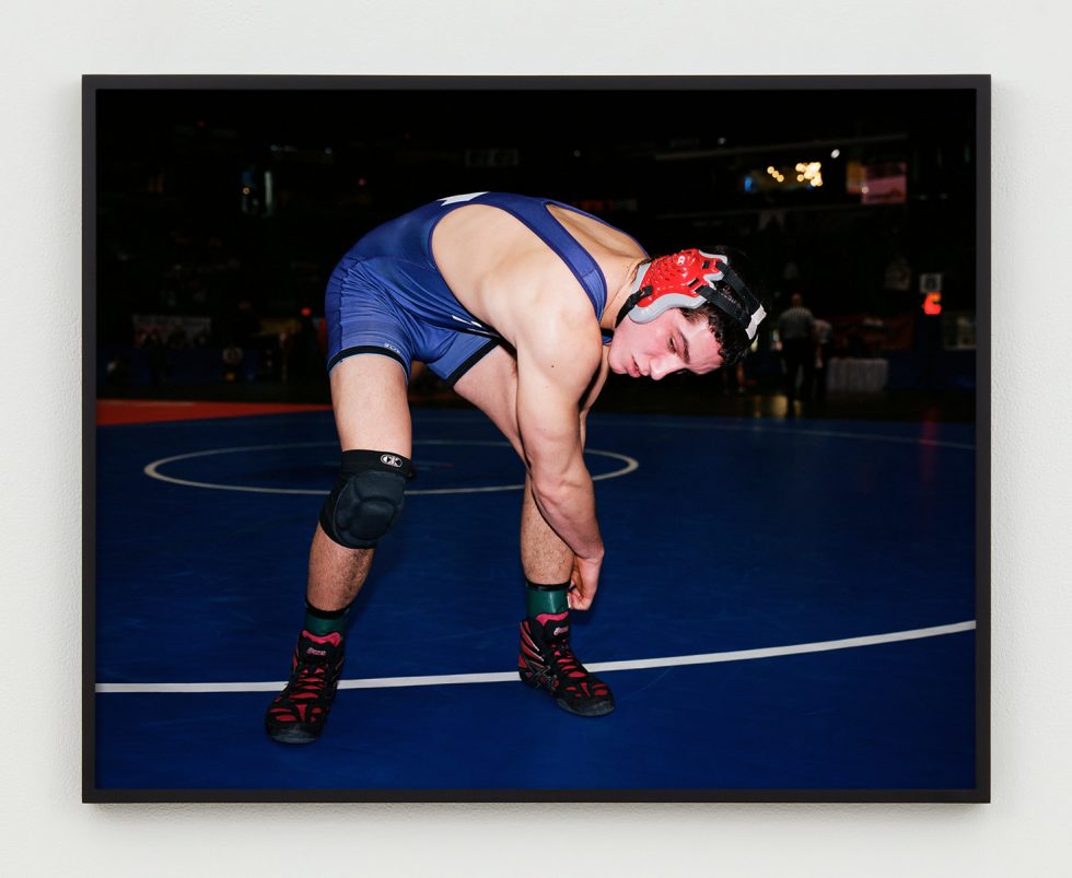 This is a photograph of a wrestler bending over adjusting his ankle straps.