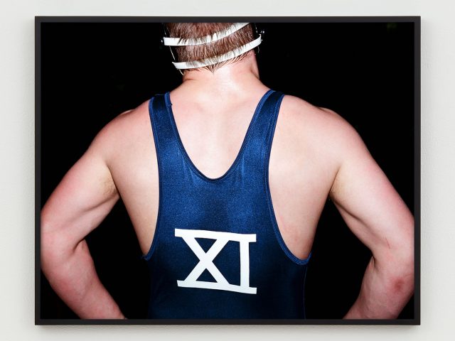 This is a photograph of the back of a wrestler with the number XI on the back of his singlet.