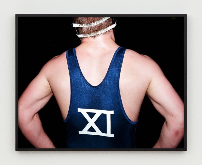 This is a photograph of the back of a wrestler with the number XI on the back of his singlet.