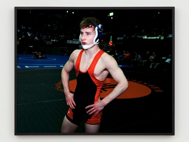 This is a photograph of a wrestler who is sweaty with a bloody lip.