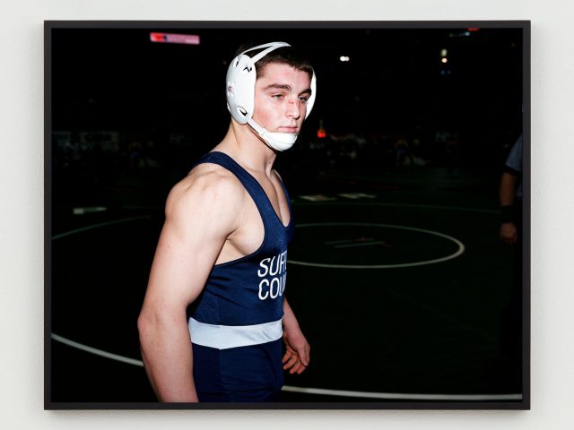 This is a photographic portrait of a young male wrestler in his gear.