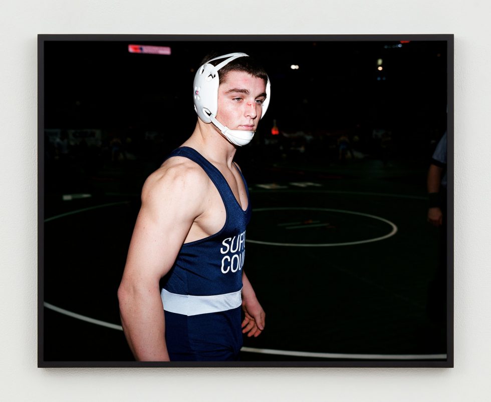 This is a photographic portrait of a young male wrestler in his gear.