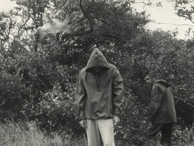 Jared French and Paul Cadmus wearing rain jackets amongst some trees