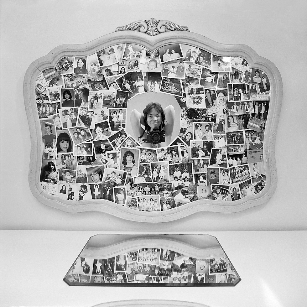 This is a photograph of a woman taking her own picture in a mirror adorned with photographs.