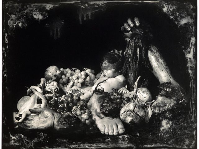 This is an elaborate black and white photographic still life by Joel-Peter Witkin titled "Feast of Fools" picturing human limbs, a baby corpse, an octopus, and fruit.