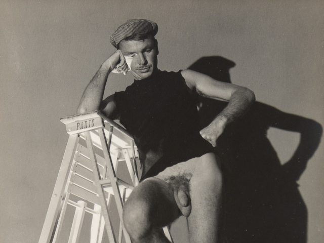 Jared French standing on a Ladder wearing a shirt and checkered hat, and no trousers