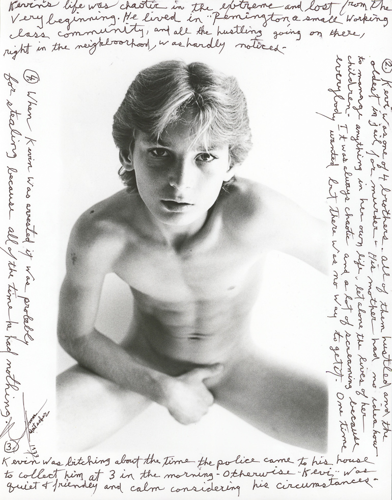 This is a black-and-white photograph of a blond young man with no clothes looking straight into the camera lens with extensive written words all around the image.