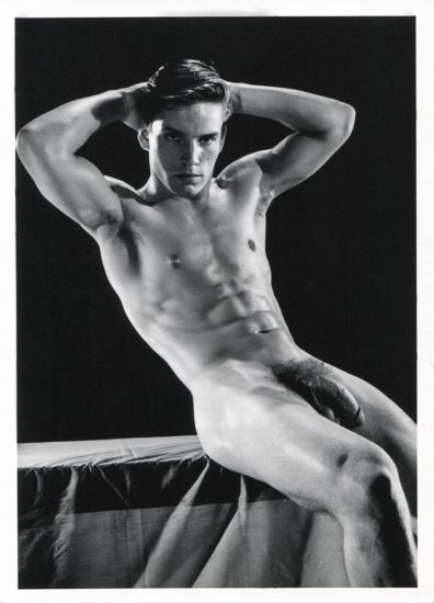 A black and white photograph by Bruce of Los Angeles of beefcake model Joe Dallesandro posing nude with his hands on his head.