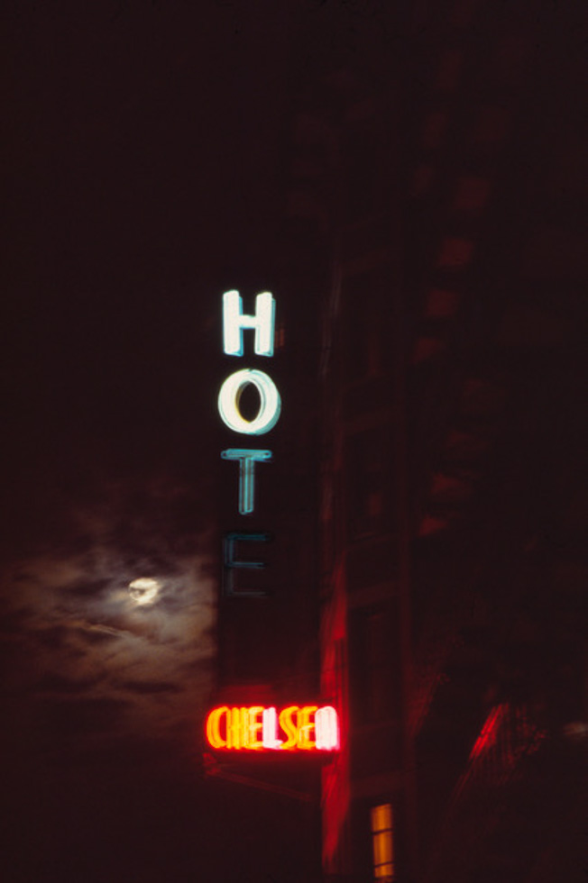 The Chelsea Hotel neon sign partially lit up, displaying HOT Chelsea taken by Linda Troeller