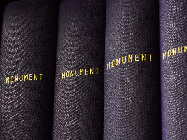 This is a photograph of black book spines which all say "MONUMENT," taken by artist Mickey Smith.