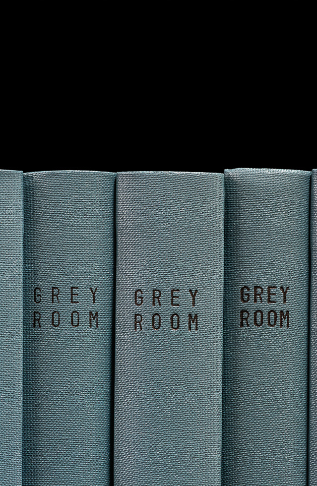 This is a photograph of grey book spines which all say "GREY ROOM," taken by artist Mickey Smith.